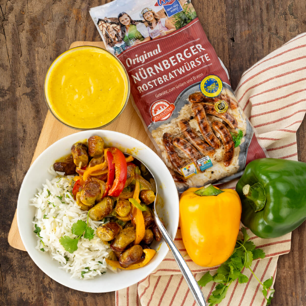 Buntes Curry aus dem Wok mit WOLF Original Nürnberger Rostbratwürste, Paprika, Zwiebel und Currysauce. Dazu Reis mit Koriander.