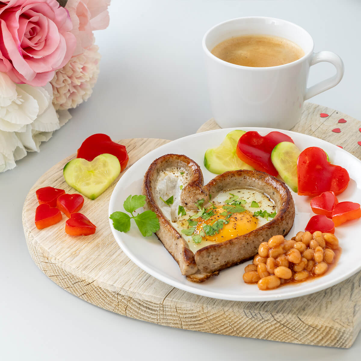 Frühstücksteller mit einem Bratwurstherz gefüllt mit Spiegelei. Dazu Gemüse in Herzform und Baked Beans
