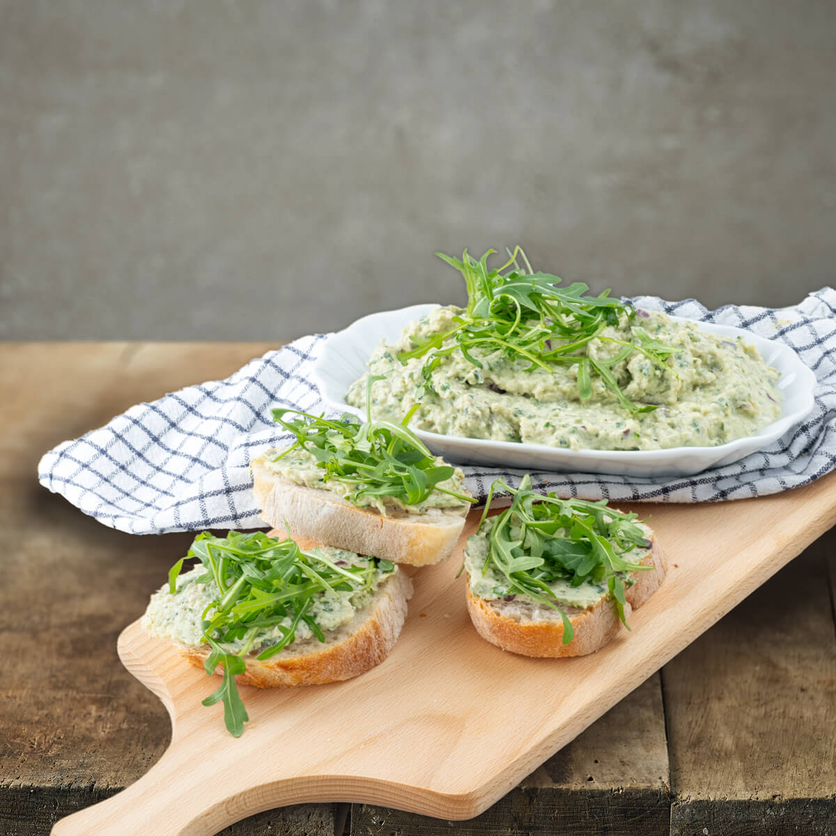 Frühlingsaufstrich mit Rucola und Thüringer Kochschinken garniert auf Baguettebrot