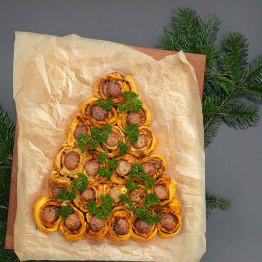 Thüringer Rostbratwürste eingewickelt in Blätterteig und in Tannenbaum-Form auf Backpapier ausgelegt.