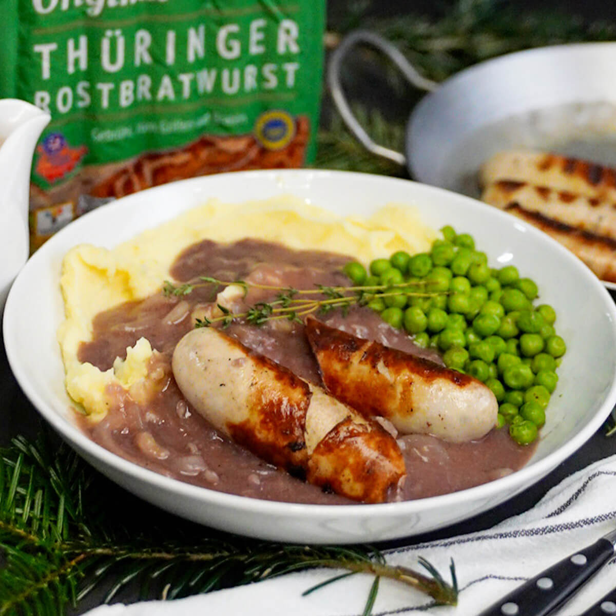 Thüringer Rostbratwürste auf Zwiebelsoße und Kartoffelbrei mit Erbsen