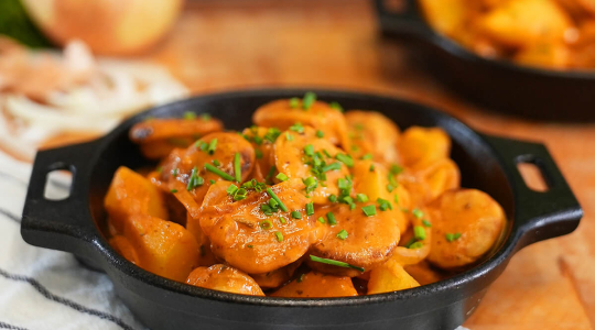 Ein Gefäß mit einem Gulasch aus Thüringer Rostbratwurst und Kartoffeln, mit Soße und Schnittlauch