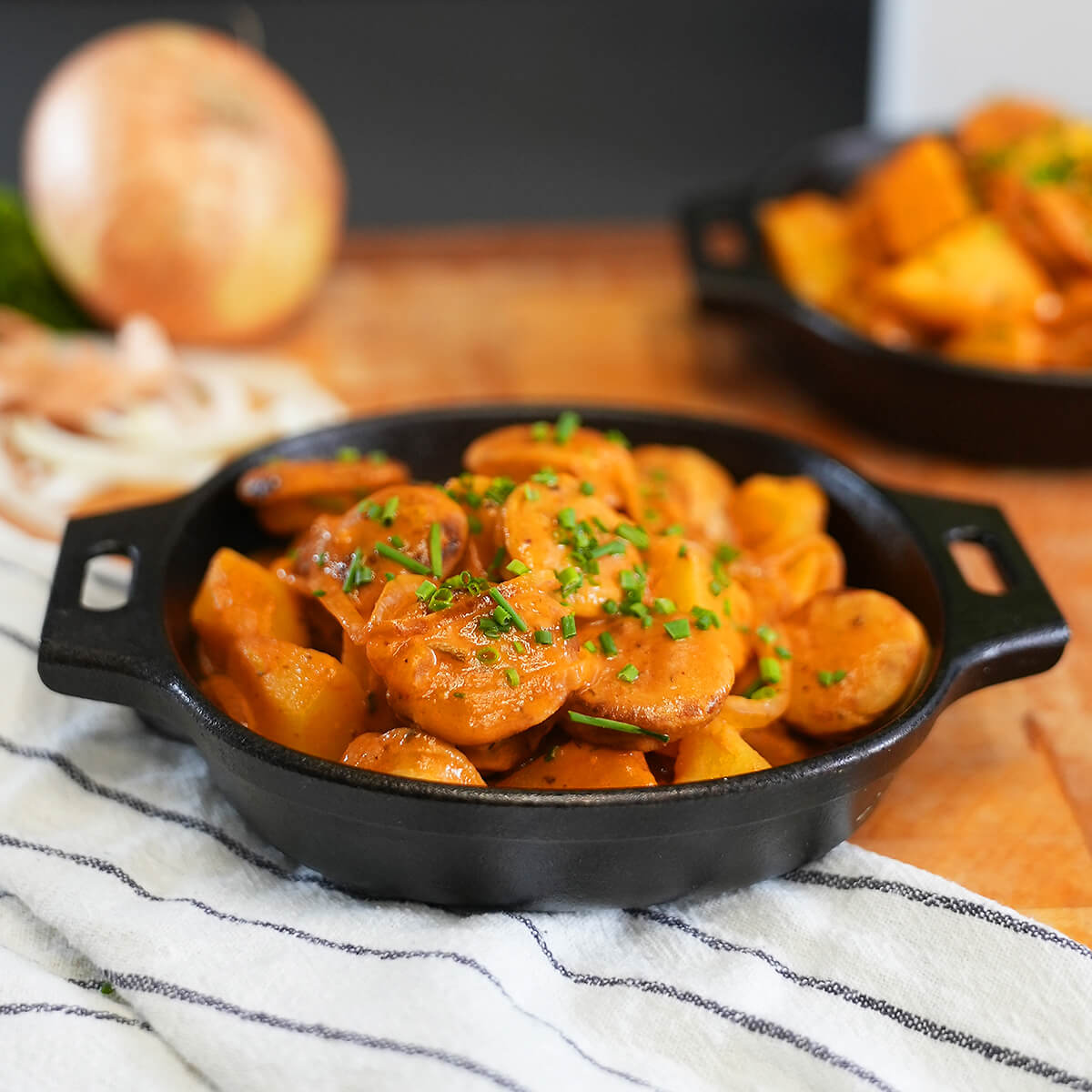 Ein Gefäß mit einem Gulasch aus Thüringer Rostbratwurst und Kartoffeln, mit Soße und Schnittlauch