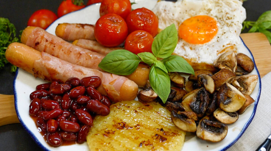 Englisches Frühstück mit Berner Würstchen, Roundies, Baked Beats, Champions, Tomaten und Spiegelei auf Toast