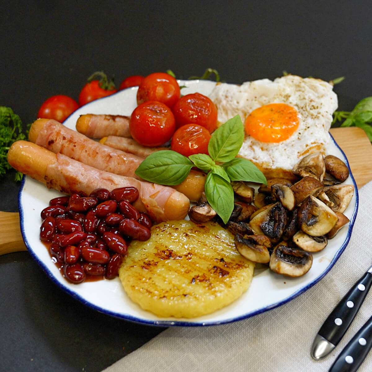 Englisches Frühstück mit Berner Würstchen, Roundies, Baked Beats, Champions, Tomaten und Spiegelei auf Toast