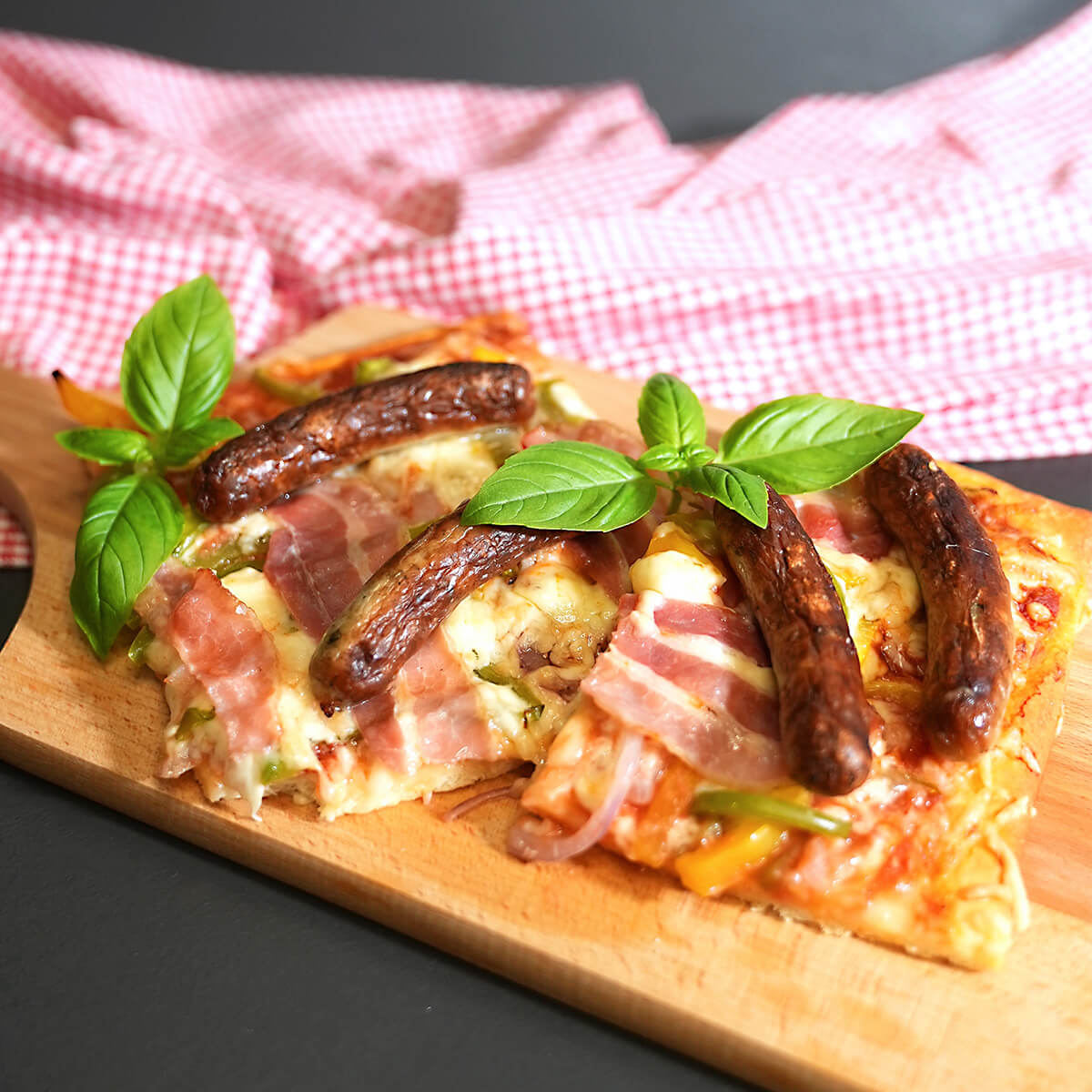 Pizza mit Nürnberger Rostbratwürsten und Bacon .