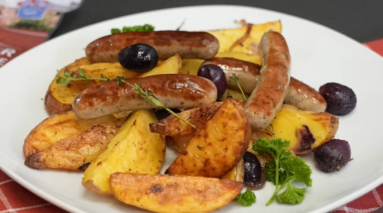 Nürnberger Bratwürste mit Kartoffelspalten und Trauben aus dem Ofen