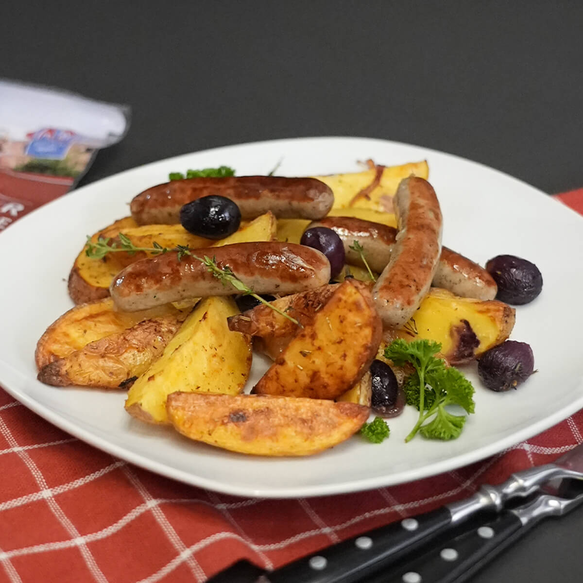 Nürnberger Bratwürste mit Kartoffelspalten und Trauben aus dem Ofen