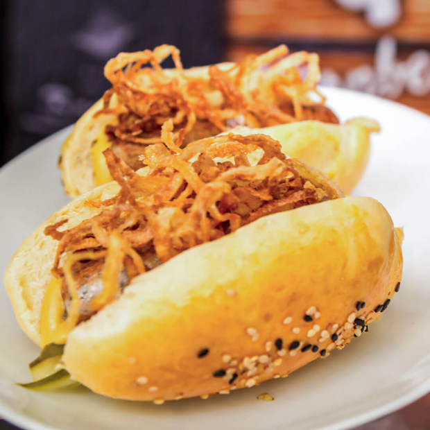 Hotdog gefüllt mit Nürnberger, Gewürzgurken und Röstzwiebel.