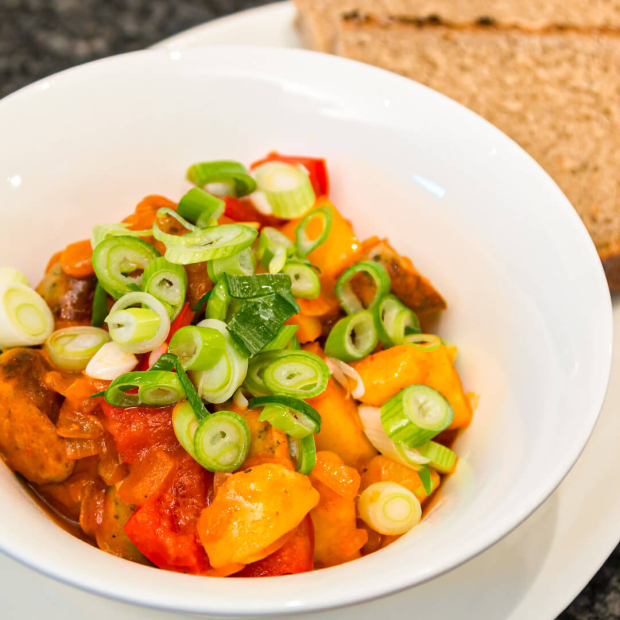Gulasch aus Kartoffeln, Paprika, Zwiebel und Nürnberger Würstchen getoppt mit Frühlingszwiebel.